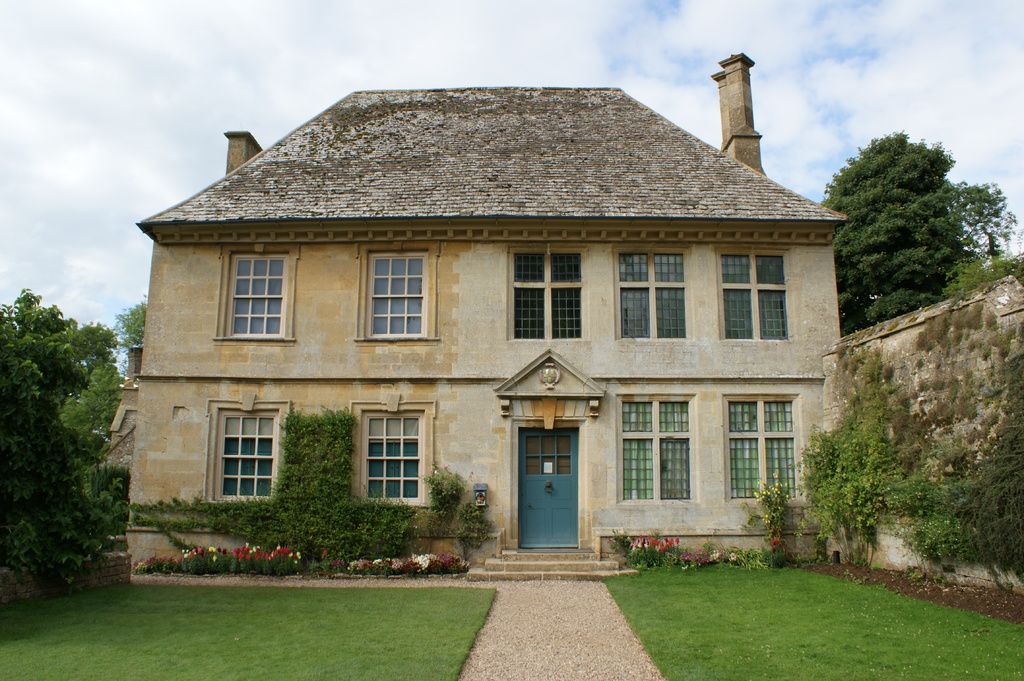 A stone manor house with a teal front door and neat front garden