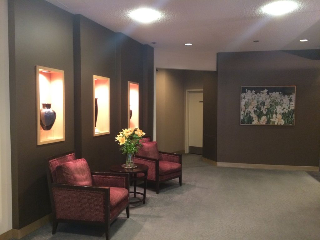 A modern lounge with charcoal walls, lit display niches and deep red armchairs